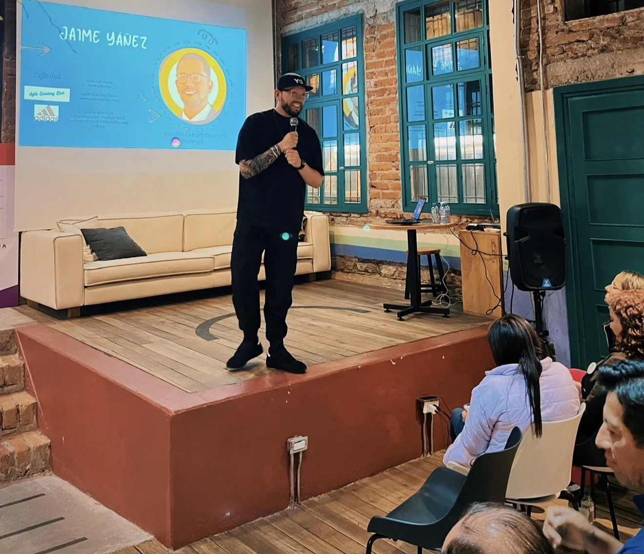 Jaime Yáñez educando en un escenario con su presentación proyectada